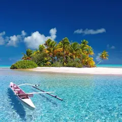 Tropikalna wyspa z palmami, białą plażą i łodzią na turkusowej wodzie.