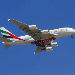 Ogromny samolot Emirates z wysuniętym podwoziem, gotowy do lądowania. Idealny do przewozu bagażu podręcznego.