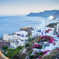Widok na białe domy Santorini z niebieskimi drzwiami i oknami, kwitnące bugenwille. Czy do Grecji potrzebny jest paszport? Tak, jeśli nie jesteś obywatelem UE.