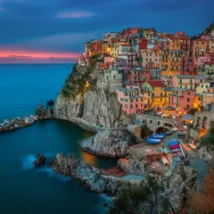 Manarola, jedno z najpiękniejszych miejsc nad morzem we Włoszech, zachwyca kolorowymi domami na klifie o zachodzie słońca.