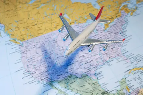 Samolot nad mapą USA. Zastanawiasz się, ile kosztuje bilet do USA w dwie strony?