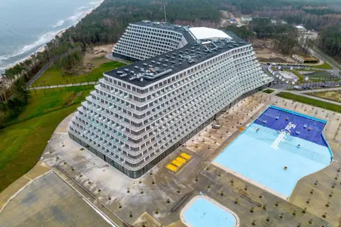 Widok z lotu ptaka na nowoczesny hotel Gołębiewski w Pobierowie z basenem i morzem w tle.