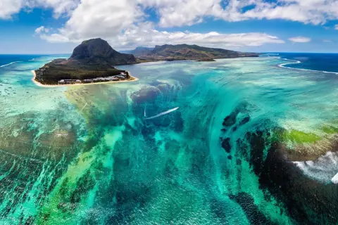 Podwodny wodospad na Mauritiusie, marzenie o wizie do raju. Turkusowa woda, góry i łódź.