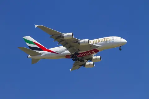 Ogromny samolot Emirates z wysuniętym podwoziem, gotowy do lądowania. Idealny do przewozu bagażu podręcznego.