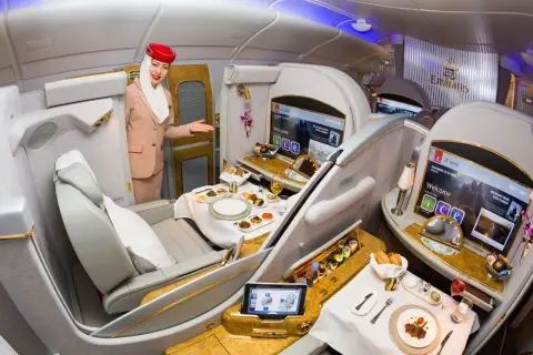 Stewardessa Emirates wita pasażera w luksusowej kabinie, oferując posiłek i rozrywkę. To szczyt komfortu podróży, oferowany przez jedne z największych linii lotniczych.