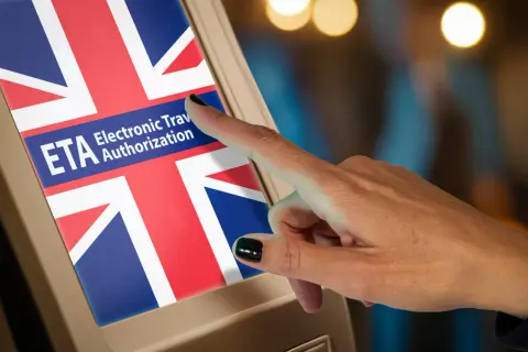 Palec dotyka ekranu z flagą Wielkiej Brytanii i napisem "ETA Electronic Travel Authorization". To krok do uzyskania wizy do Londynu.