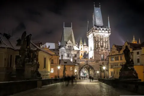 Most Karola w Pradze nocą, ośnieżony, z wieżami i rzeźbami. Idealne miejsce na wycieczki objazdowe po Europie.
