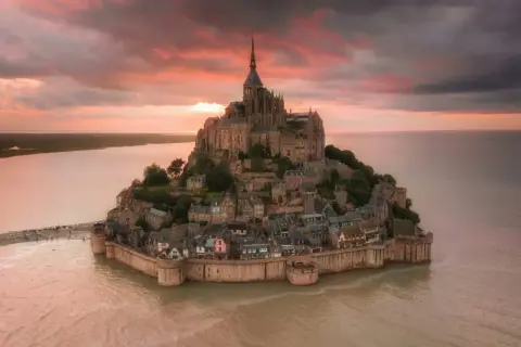 Bajkowy zamek na wodzie we Francji, Mont Saint-Michel, w blasku zachodzącego słońca.