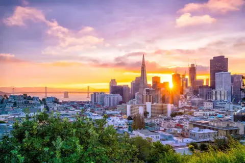 Zachód słońca nad San Francisco, idealne miejsce na wakacje w Stanach Zjednoczonych. Most Golden Gate i drapacze chmur w złotej poświacie.