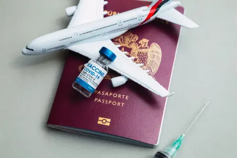 Podróż do Kenii? Pamiętaj o szczepieniach! Paszport, samolot i szczepionka COVID-19 symbolizują bezpieczne podróżowanie.