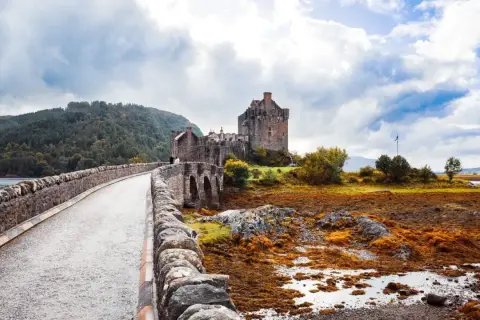 Kamienny most prowadzi do zamku Eilean Donan, ikony Szkocji. Wiza do Szkocji to marzenie wielu podróżników.
