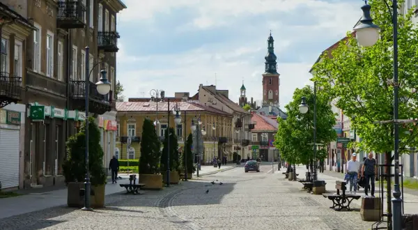 Ulica w Radomiu z kamienicami, wieżą kościelną i zielenią.