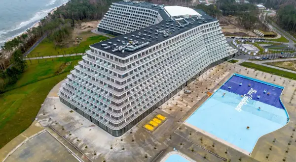 Widok z lotu ptaka na nowoczesny hotel Gołębiewski w Pobierowie z basenem i morzem w tle.