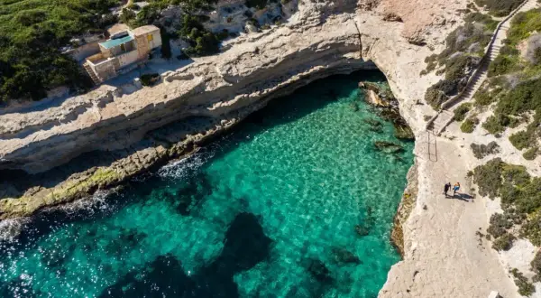Malta plaże: turkusowa woda w zatoce, skaliste wybrzeże i schody prowadzące do ukrytej plaży.