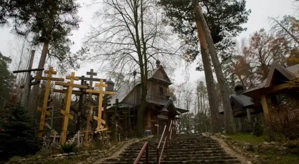 Kamienna ścieżka prowadzi do drewnianej cerkwi, otoczonej gęsto ustawionymi krzyżami. To miejsce pamięci, gdzie każdy krzyż to historia.