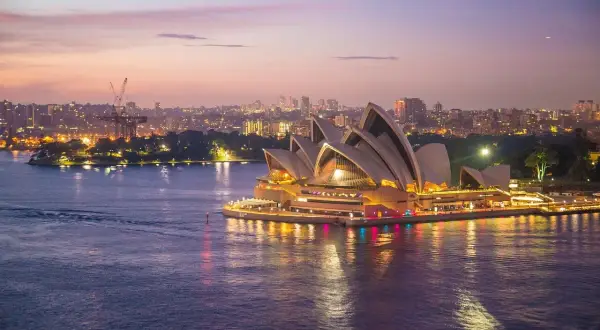 Zachód słońca nad Operą w Sydney. Marzenie o wizie do Australii staje się rzeczywistością, gdy miasto rozświetla się nocą.