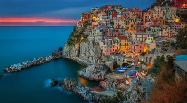 Manarola, jedno z najpiękniejszych miejsc nad morzem we Włoszech, zachwyca kolorowymi domami na klifie o zachodzie słońca.