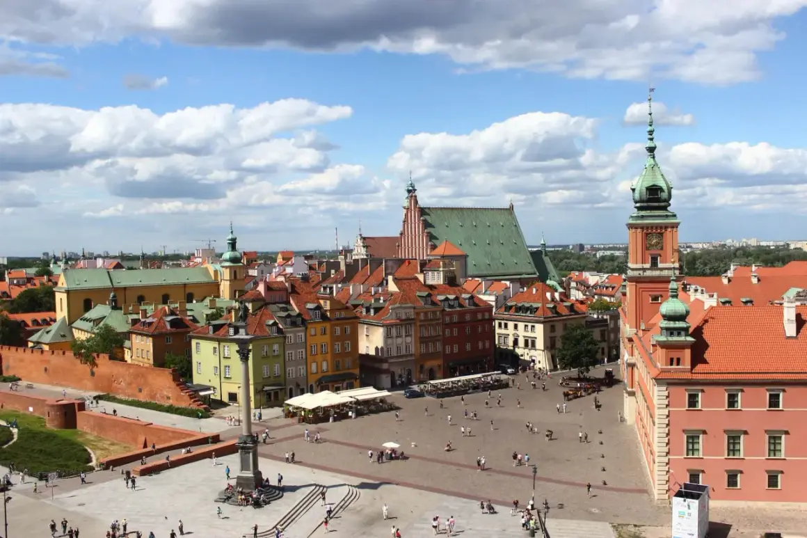 Widok na Zamek Królewski i Kolumnę Zygmunta III Wazy na placu w warszawskiej starówce. Tłumy spacerują po bruku, a słońce przebija się przez chmury.