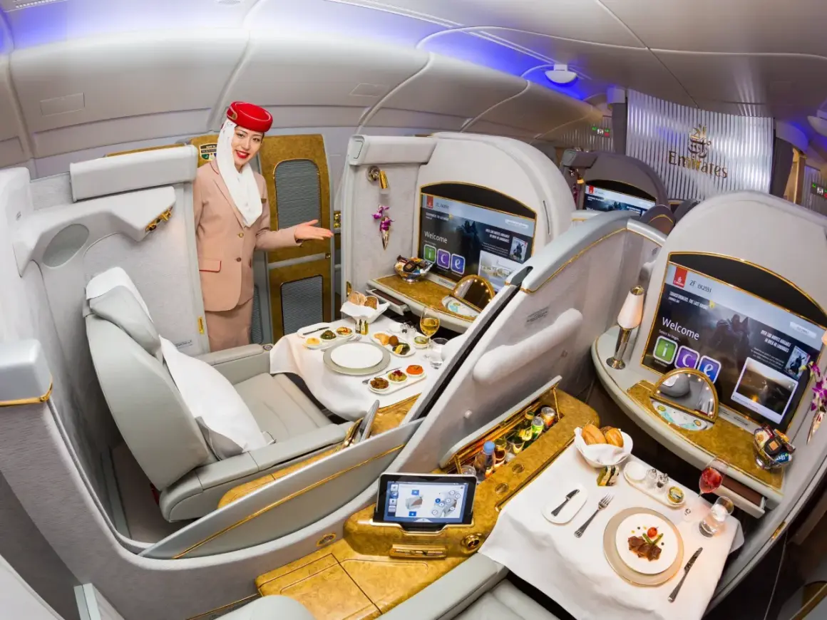 Stewardessa Emirates wita pasażera w luksusowej kabinie, oferując posiłek i rozrywkę. To szczyt komfortu podróży, oferowany przez jedne z największych linii lotniczych.