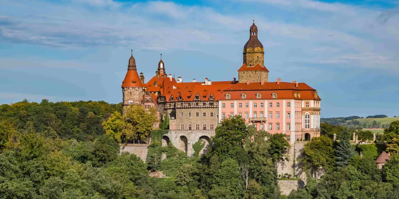 Zamek Książ, bajkowa budowla na wzgórzu, to miejsce, gdzie warto pojechać w Polsce. Otoczony zielenią, zachwyca architekturą.