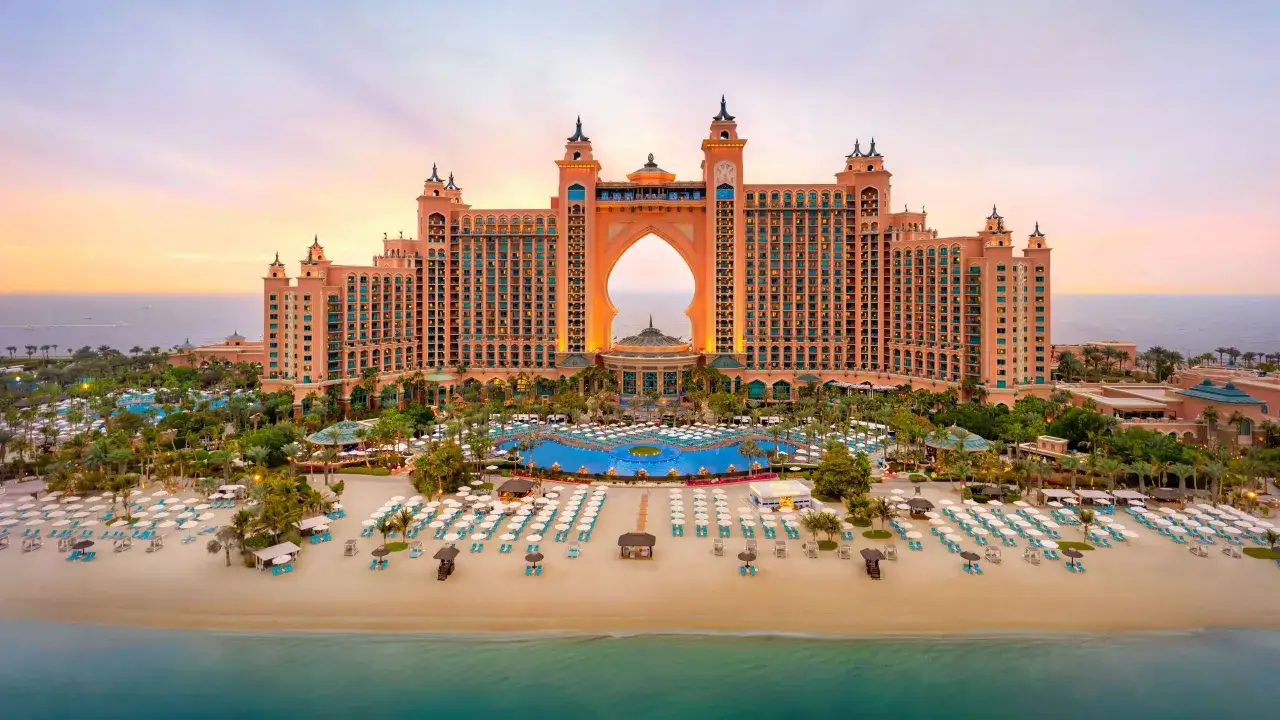 Hotel Atlantis w Dubaju o zachodzie słońca, z plażą, basenami i palmami.