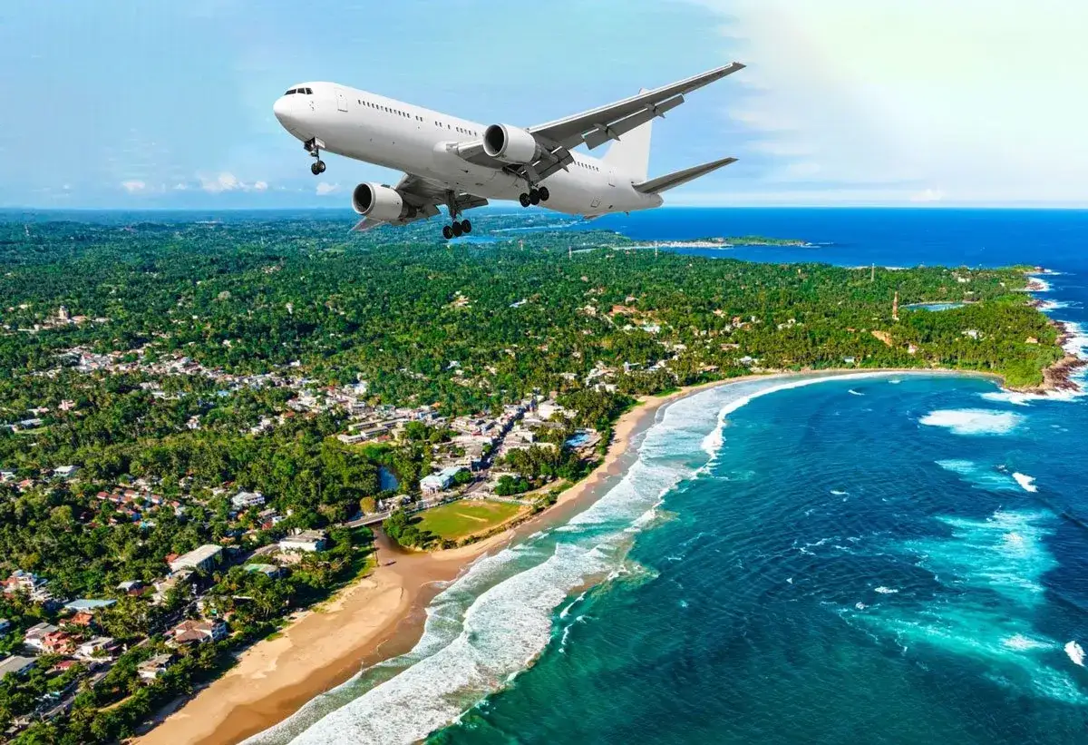 Samolot zbliża się do wybrzeża Sri Lanki, nad zieloną dżunglą i turkusowym oceanem. Loty Sri Lanka to początek niezapomnianej podróży.