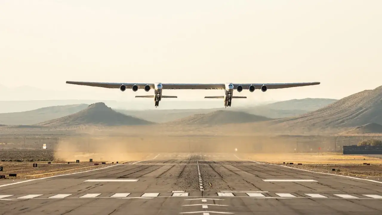 Największy samolot na świecie, Stratolaunch, wzbija się w powietrze nad pustynnym krajobrazem.