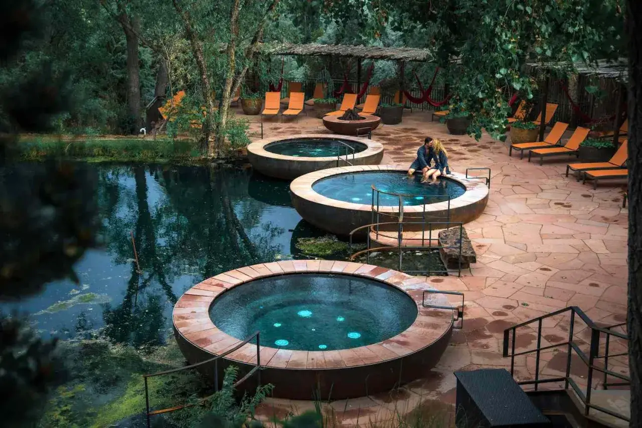 Para relaksu w belgijskim kurorcie: para w jacuzzi, baseny termalne, leżaki i bujna zieleń.