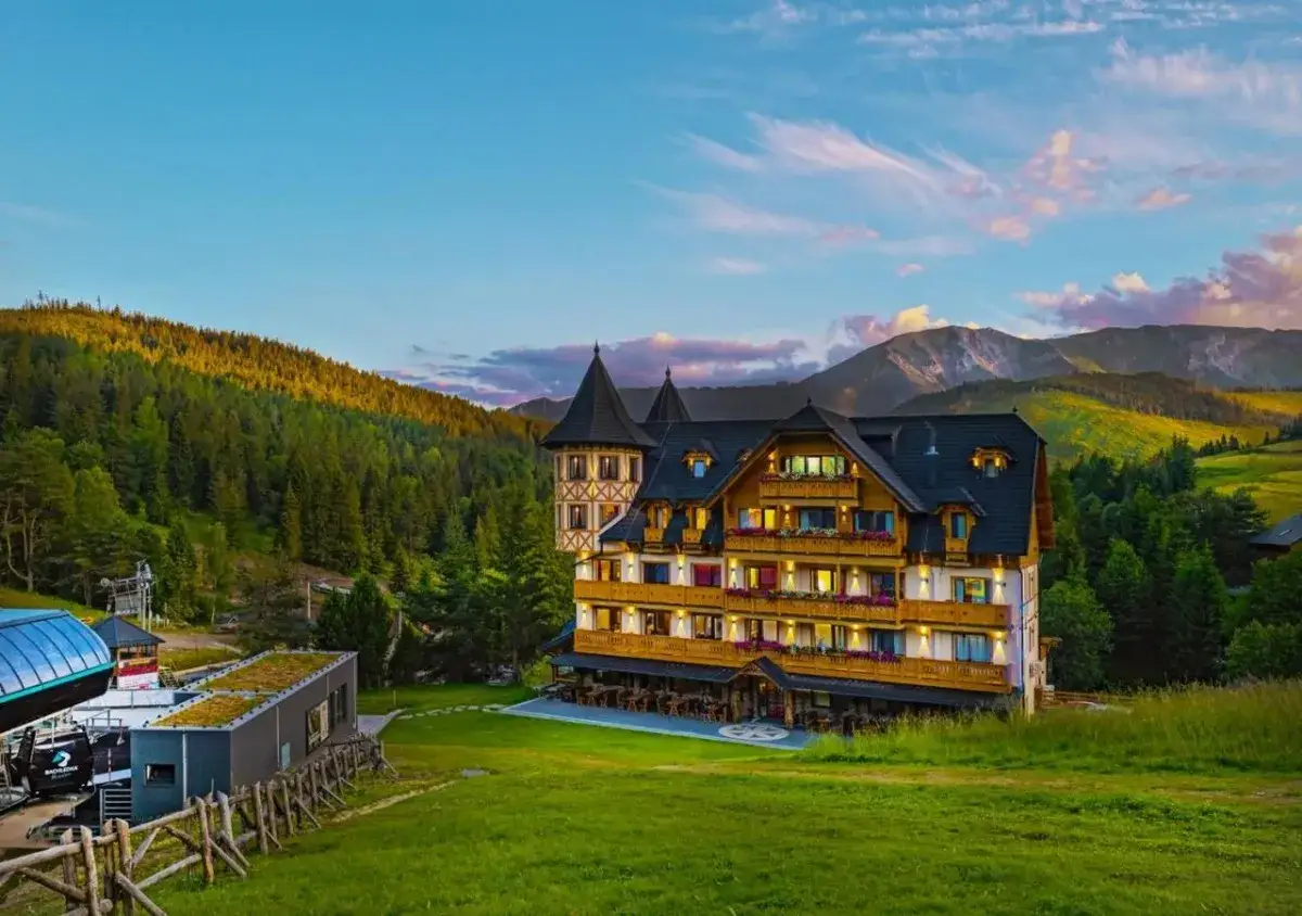 Drewniany hotel w górach, obok kolejki linowej. Widok na Tatry Słowackie z Bachledki o zachodzie słońca.