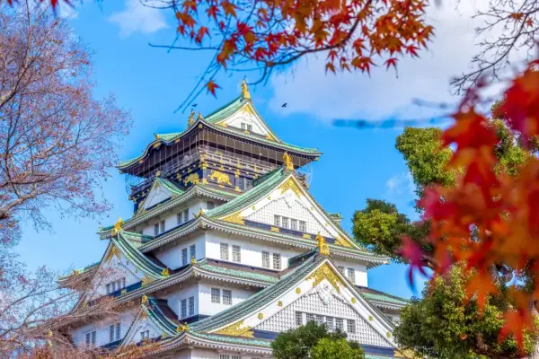 Piękny zamek w Osace, idealne miejsce na wycieczkę do Japonii. Jesienne liście dodają uroku.