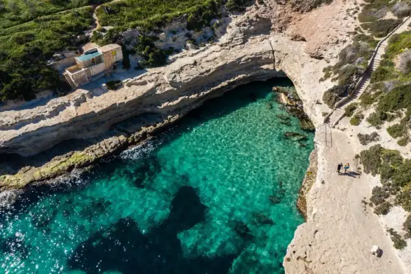 Malta plaże: turkusowa woda w zatoce, skaliste wybrzeże i schody prowadzące do ukrytej plaży.