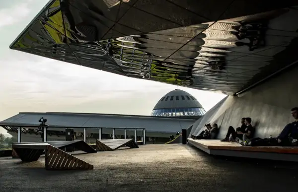 Nowoczesna architektura i nietypowe atrakcje Katowice: ludzie odpoczywają pod futurystycznym zadaszeniem, w tle kopuła Muzeum Śląskiego.