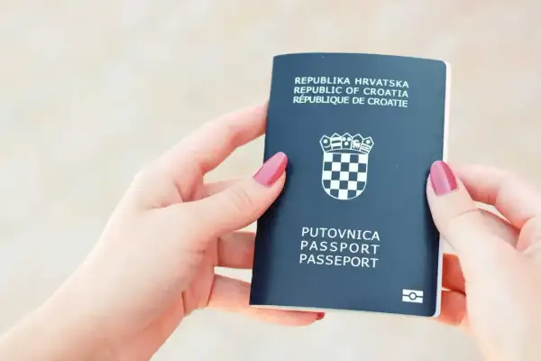 Dwie dłonie trzymają ciemnogranatowy paszport Republiki Chorwacji. Czy do Chorwacji potrzebny jest paszport? Tak, ten dokument jest niezbędny.