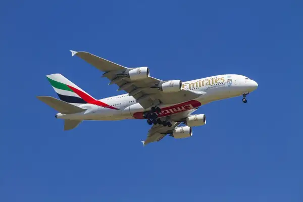 Ogromny samolot Emirates z wysuniętym podwoziem, gotowy do lądowania. Idealny do przewozu bagażu podręcznego.