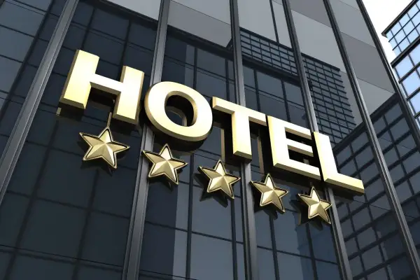 Złoty napis HOTEL i pięć gwiazdek na tle nowoczesnego budynku hotelowego.