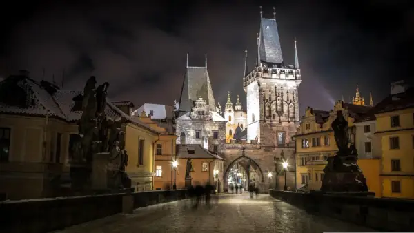 Most Karola w Pradze nocą, ośnieżony, z wieżami i rzeźbami. Idealne miejsce na wycieczki objazdowe po Europie.
